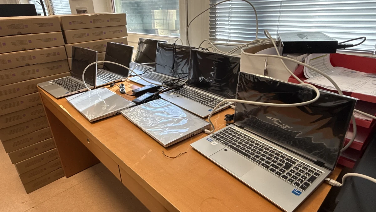 Un lot d’ordinateurs portables raccordés sur une table, avec leurs cartons à côté.